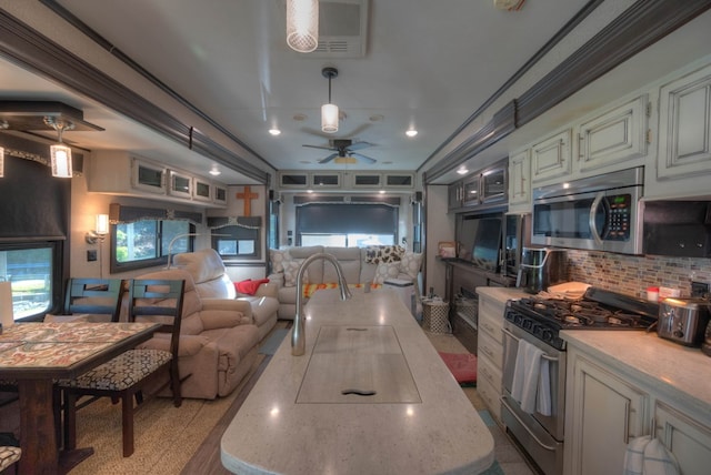kitchen featuring stainless steel appliances, open floor plan, backsplash, a ceiling fan, and a kitchen island
