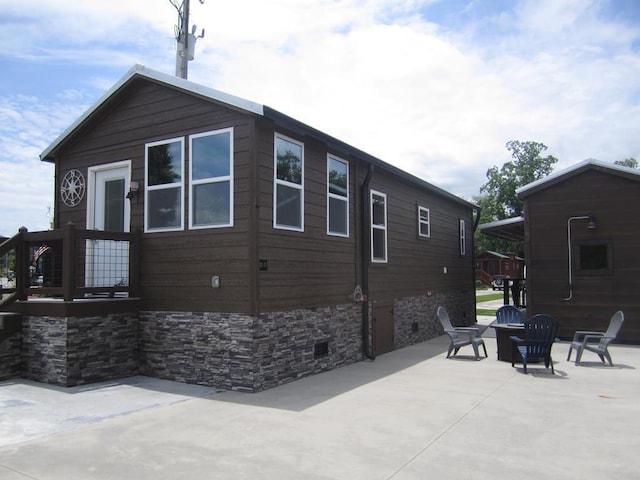 view of side of property with a fire pit and a patio area