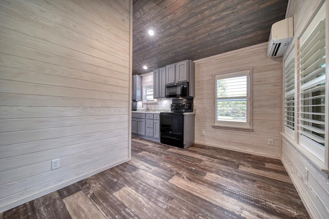 kitchen featuring black appliances, gray cabinetry, wooden walls, and a wall unit AC