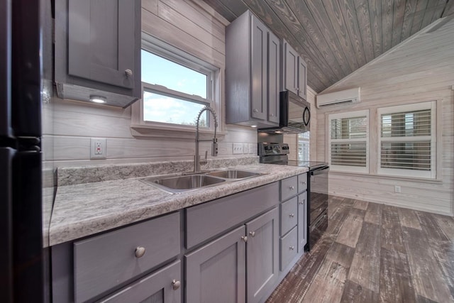 kitchen with vaulted ceiling, black appliances, wooden walls, sink, and a wall mounted air conditioner