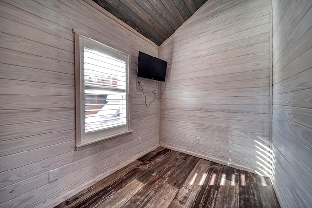 empty room with lofted ceiling, wood walls, and hardwood / wood-style floors