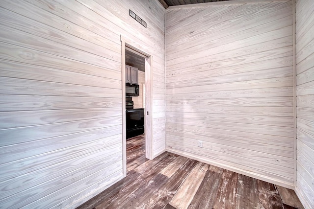 unfurnished room with wooden walls and hardwood / wood-style floors