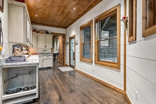 kitchen featuring light stone countertops, cream cabinets, dark hardwood / wood-style flooring, and wooden ceiling