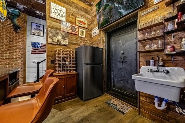 interior space featuring wooden walls, sink, hardwood / wood-style floors, and stainless steel refrigerator