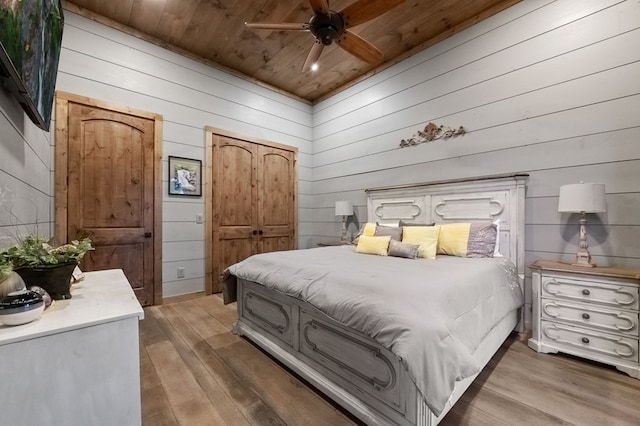 bedroom featuring ceiling fan, wooden walls, and wood ceiling