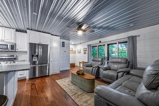 home theater with ceiling fan, dark wood-type flooring, and wood walls