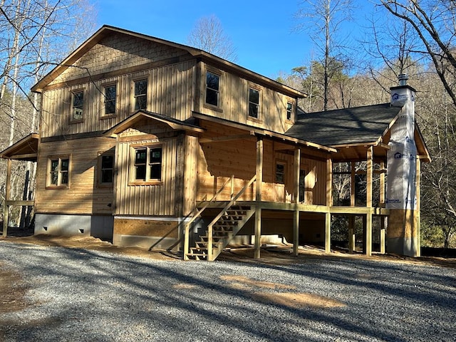 view of front of house featuring stairs, roof with shingles, and a chimney