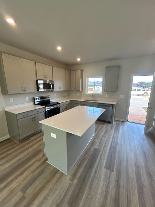 kitchen with gray cabinets, a kitchen island, dark hardwood / wood-style floors, sink, and stainless steel appliances