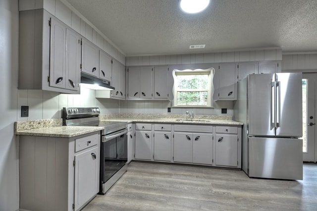 kitchen with a sink, stainless steel appliances, light countertops, and under cabinet range hood