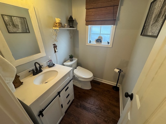 bathroom featuring visible vents, toilet, vanity, wood finished floors, and baseboards