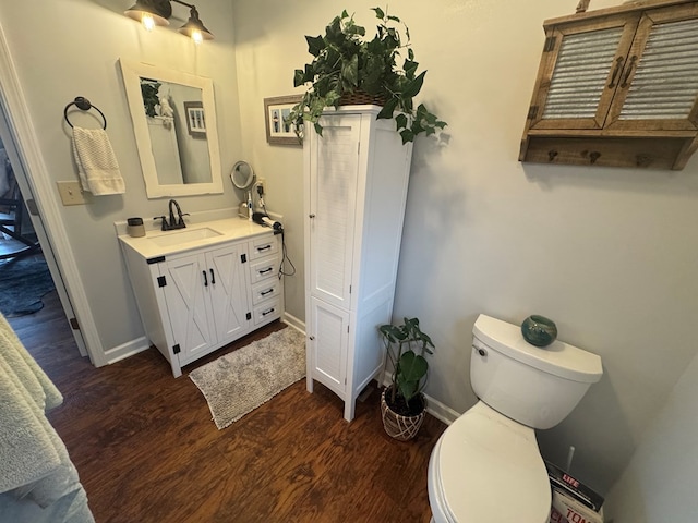 bathroom with vanity, wood finished floors, toilet, and baseboards