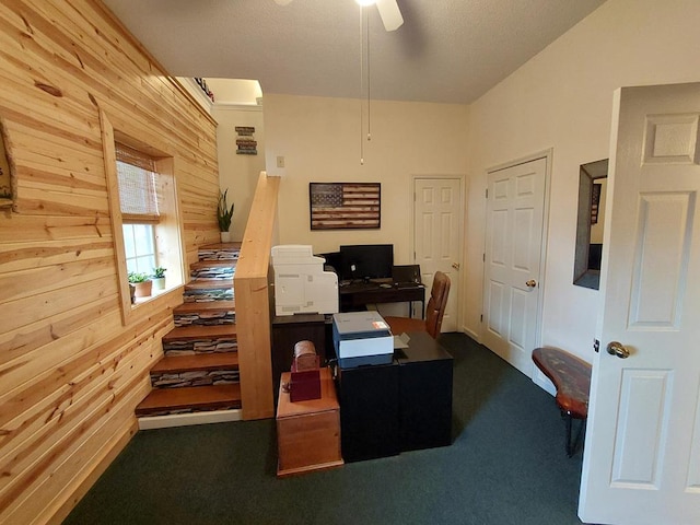 carpeted home office with wood walls and a ceiling fan