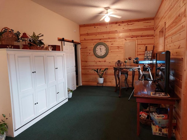 home office with a barn door, wooden walls, and ceiling fan