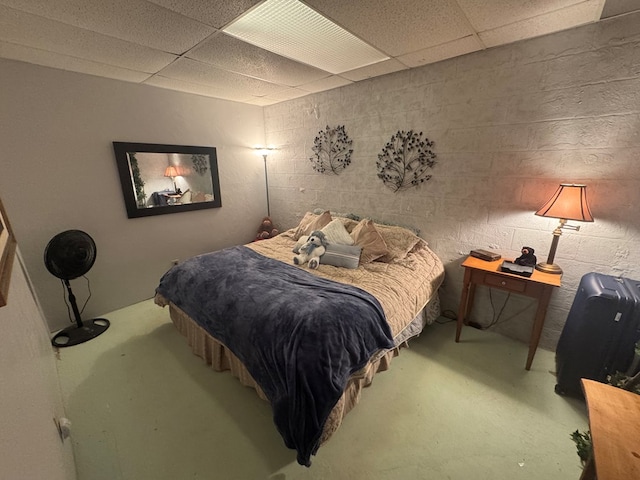 bedroom with concrete block wall and a drop ceiling