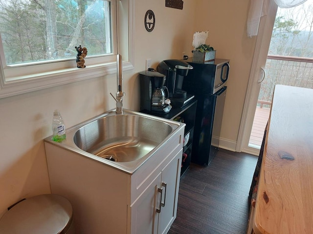 kitchen featuring dark wood-style flooring, a sink, white cabinetry, and baseboards