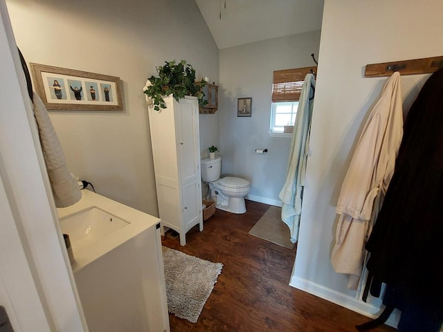 full bath with baseboards, toilet, lofted ceiling, wood finished floors, and vanity