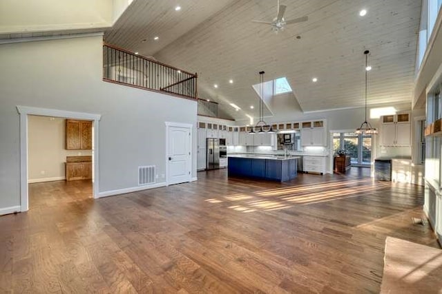 unfurnished living room featuring hardwood / wood-style flooring, ceiling fan with notable chandelier, and a high ceiling