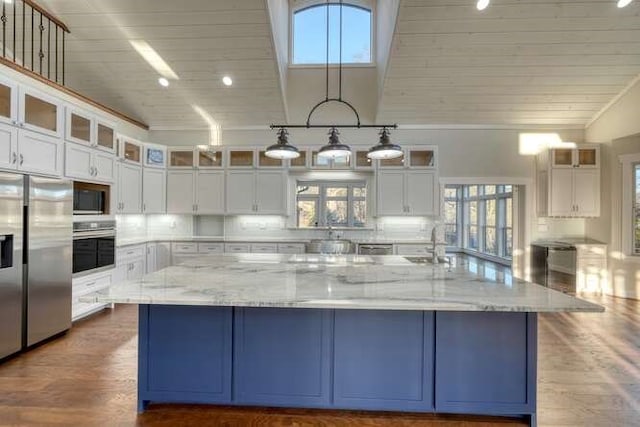 kitchen featuring light stone countertops, appliances with stainless steel finishes, white cabinets, and a spacious island