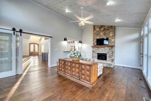 kitchen featuring a stone fireplace, ceiling fan, a barn door, dark wood-type flooring, and wooden ceiling