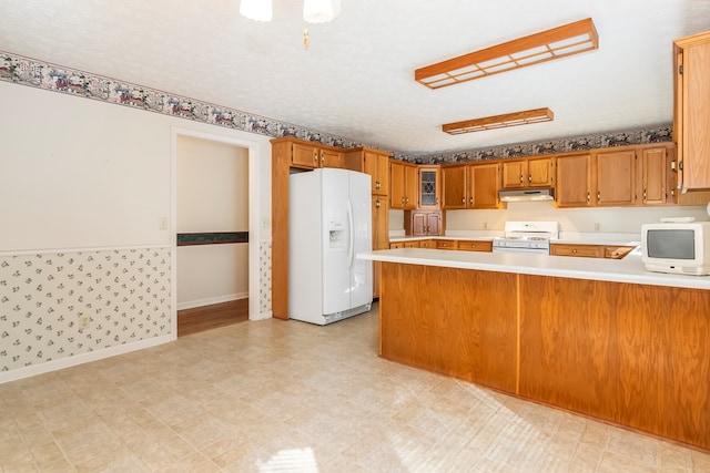 kitchen featuring white appliances, kitchen peninsula, and a textured ceiling