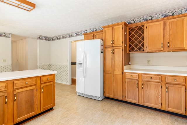 kitchen featuring a textured ceiling and white refrigerator with ice dispenser