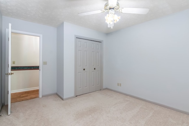 unfurnished bedroom featuring a textured ceiling, light colored carpet, ceiling fan, and a closet