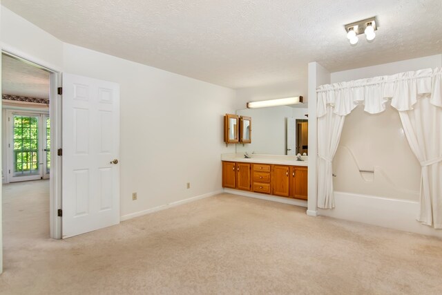 unfurnished bedroom featuring a textured ceiling, light carpet, access to exterior, connected bathroom, and sink