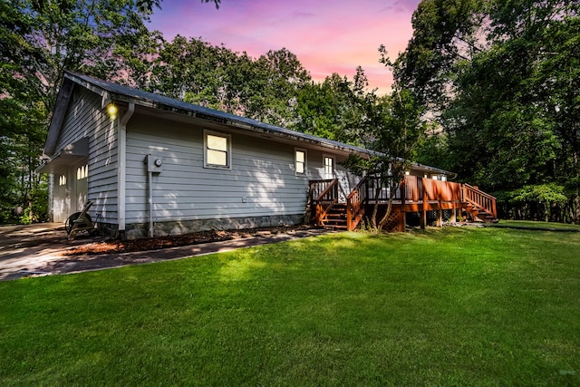 back house at dusk featuring a wooden deck, a yard, and a garage