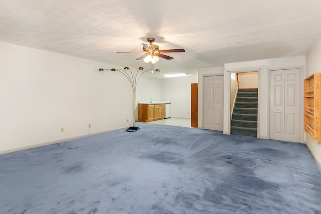 interior space with ceiling fan, light colored carpet, and a textured ceiling