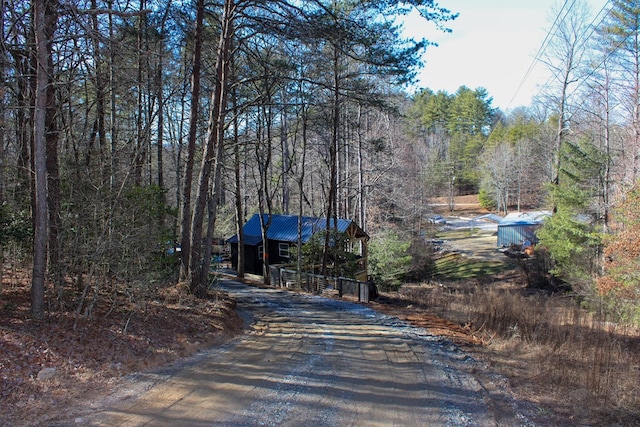 view of street with driveway and a view of trees