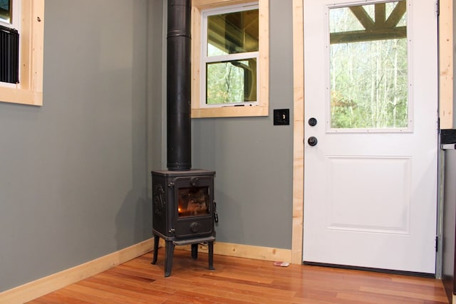 doorway featuring a wood stove, light wood-style floors, plenty of natural light, and baseboards