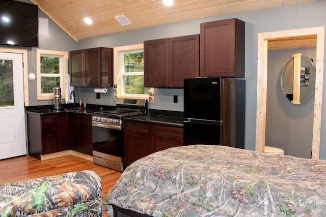 kitchen featuring lofted ceiling, visible vents, light wood-style flooring, gas stove, and freestanding refrigerator