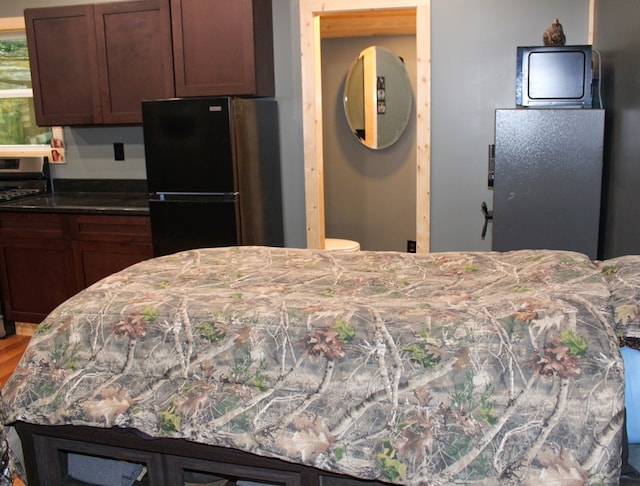 kitchen with freestanding refrigerator, stainless steel gas stove, and light stone countertops