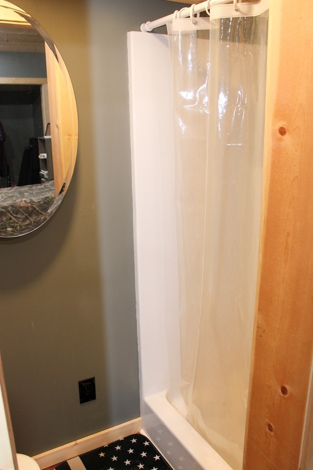 full bathroom featuring a shower stall and baseboards