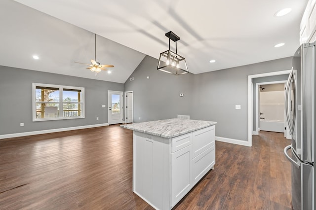 kitchen featuring hanging light fixtures, white cabinetry, light stone countertops, and stainless steel refrigerator