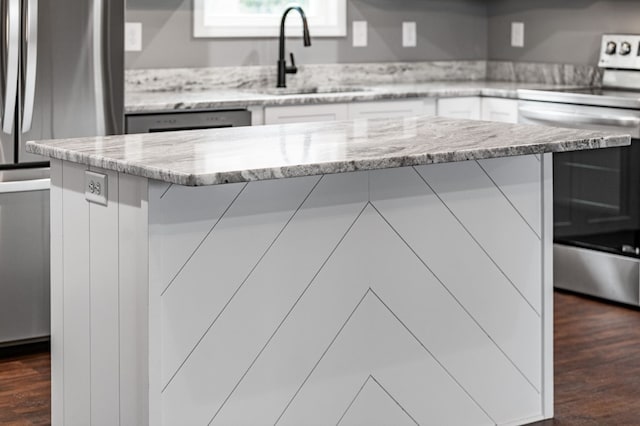 kitchen featuring sink, dark wood-type flooring, appliances with stainless steel finishes, white cabinetry, and light stone countertops