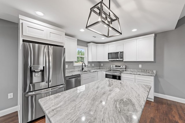 kitchen with sink, hanging light fixtures, a kitchen island, stainless steel appliances, and white cabinets