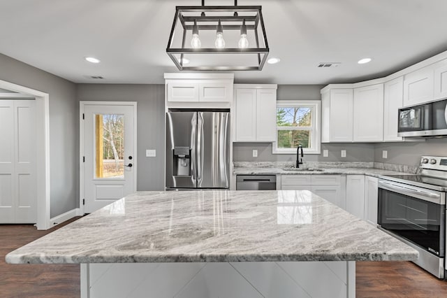 kitchen featuring a kitchen island, white cabinetry, sink, hanging light fixtures, and stainless steel appliances