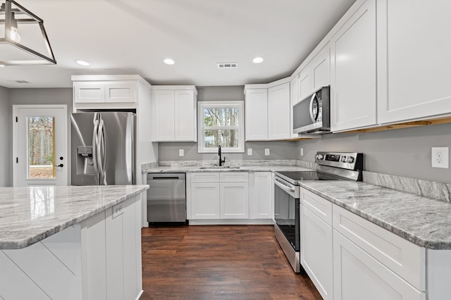 kitchen with dark wood-type flooring, sink, white cabinetry, appliances with stainless steel finishes, and light stone countertops