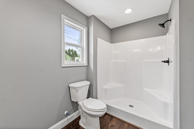 bathroom with hardwood / wood-style flooring, toilet, and walk in shower