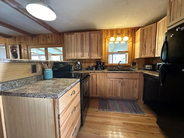 kitchen with light wood-style flooring, beam ceiling, a sink, and black appliances