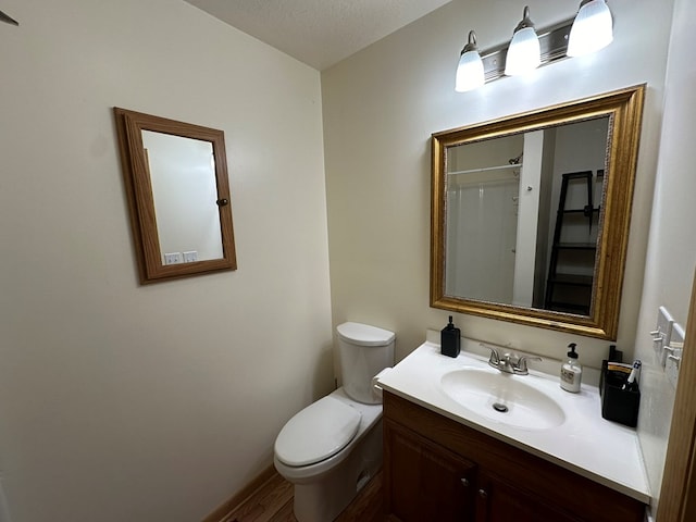 bathroom featuring toilet, a textured ceiling, hardwood / wood-style flooring, and vanity