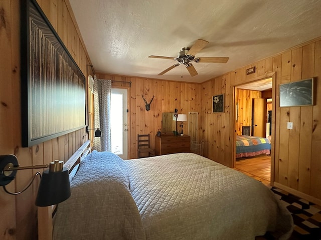 bedroom with ceiling fan, a textured ceiling, wooden walls, and access to exterior