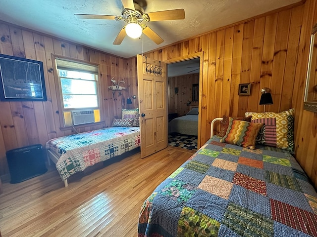 bedroom featuring hardwood / wood-style flooring, wooden walls, and ceiling fan