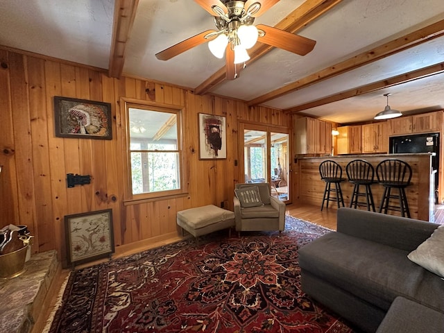 living room with a healthy amount of sunlight, beamed ceiling, and wood walls