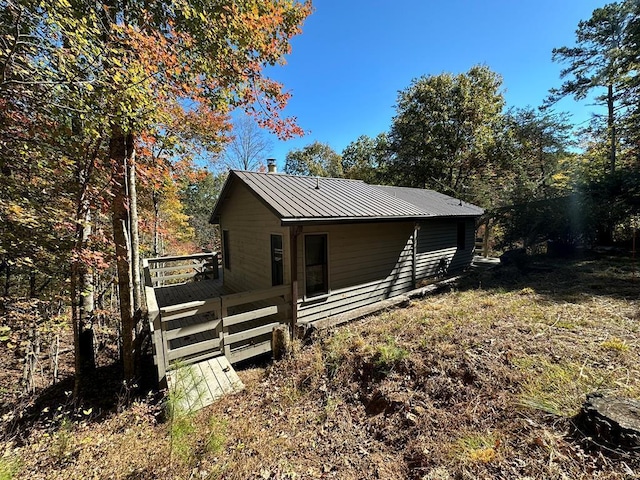 rear view of house with a chimney, a standing seam roof, a deck, and metal roof