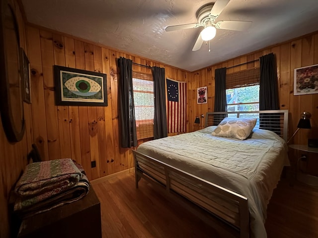 bedroom with hardwood / wood-style flooring, wooden walls, and ceiling fan