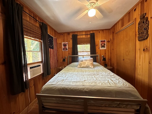bedroom with wooden walls, a ceiling fan, and cooling unit