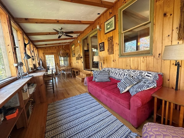 living room with ceiling fan, wood walls, plenty of natural light, and hardwood / wood-style floors