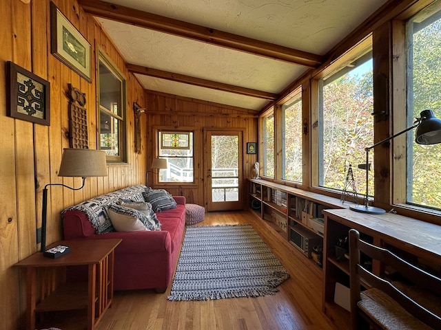sunroom / solarium with wood finished floors, vaulted ceiling with beams, and wood walls